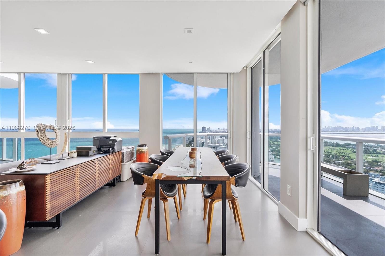 A dining room with a live-edge table, modern chairs, and floor-to-ceiling windows overlooking the ocean — 6365 Collins Ave # 4307, Miami Beach FL 33141, MIAMI BEACH, FL