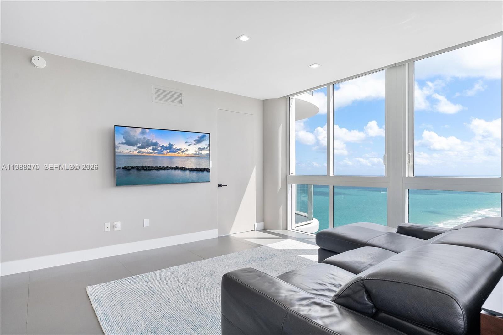 A living room features a wall-mounted television, a leather sectional, and floor-to-ceiling ocean views — 6365 Collins Ave # 4307, Miami Beach FL 33141, MIAMI BEACH, FL