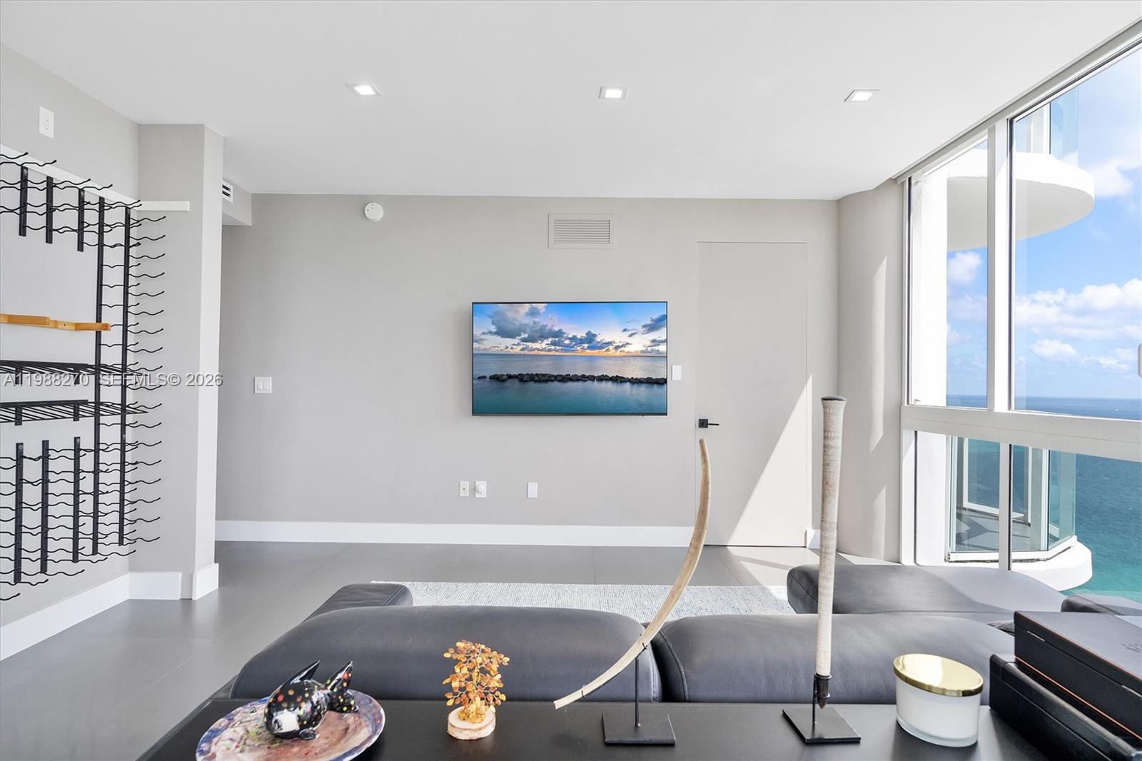 A modern living room features a wall-mounted television, a wine rack, and floor-to-ceiling windows — 6365 Collins Ave # 4307, Miami Beach FL 33141, MIAMI BEACH, FL