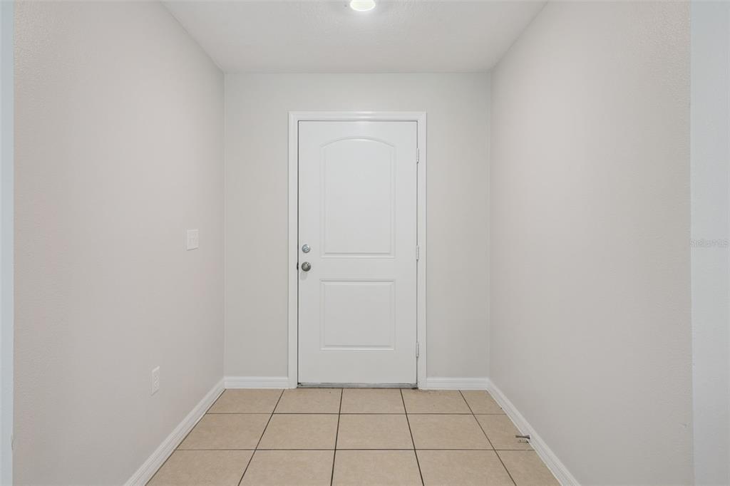 An entryway features light gray walls, a white door, and beige tiled flooring — 35685 ROSE MOSS AVENUE, LEESBURG, FL