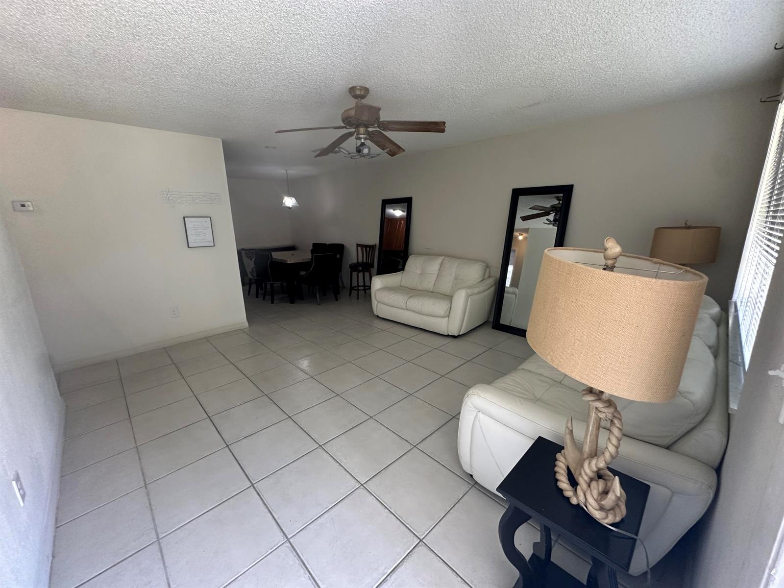 A living room with white tile floors, white leather sofas, and a nautical-themed table lamp — 422 Caroline Avenue, FL 33413, FL