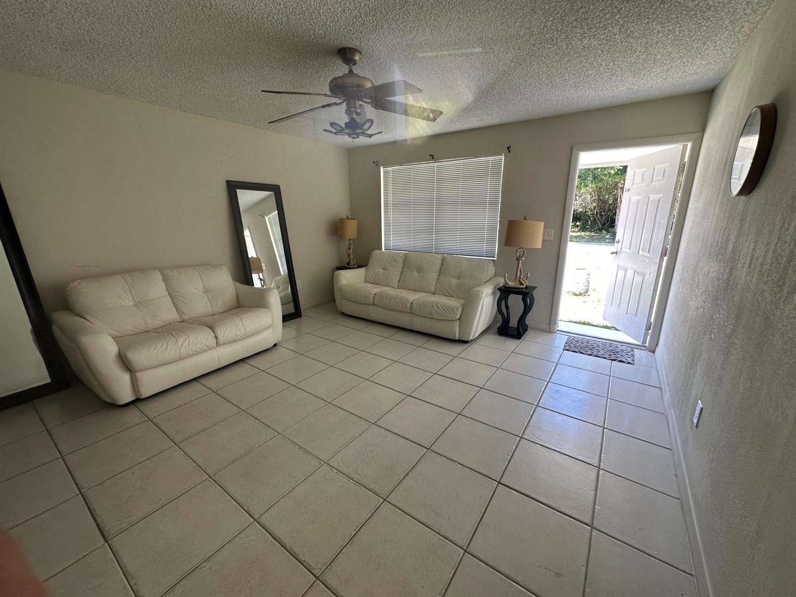 A living room with two white sofas, tile flooring, a ceiling fan, and an open door — 422 Caroline Avenue, FL 33413, FL
