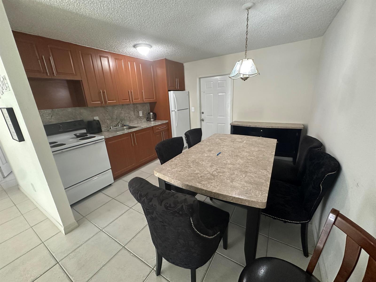 A kitchen and dining area features wood cabinets, a white stove, and a stone-topped table — 422 Caroline Avenue, FL 33413, FL