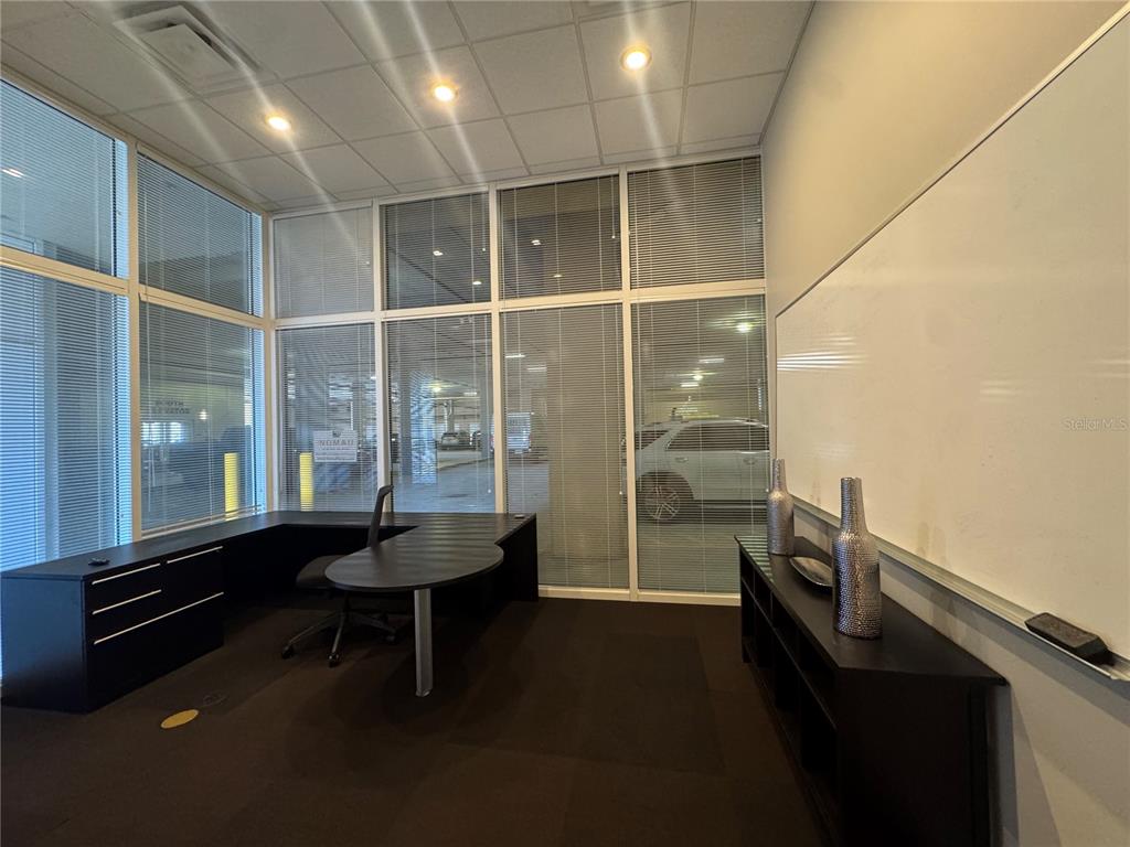 An office with a desk, a whiteboard, and large windows overlooking a parking garage — 1112 CHANNELSIDE DRIVE UNIT CU3, TAMPA, FL