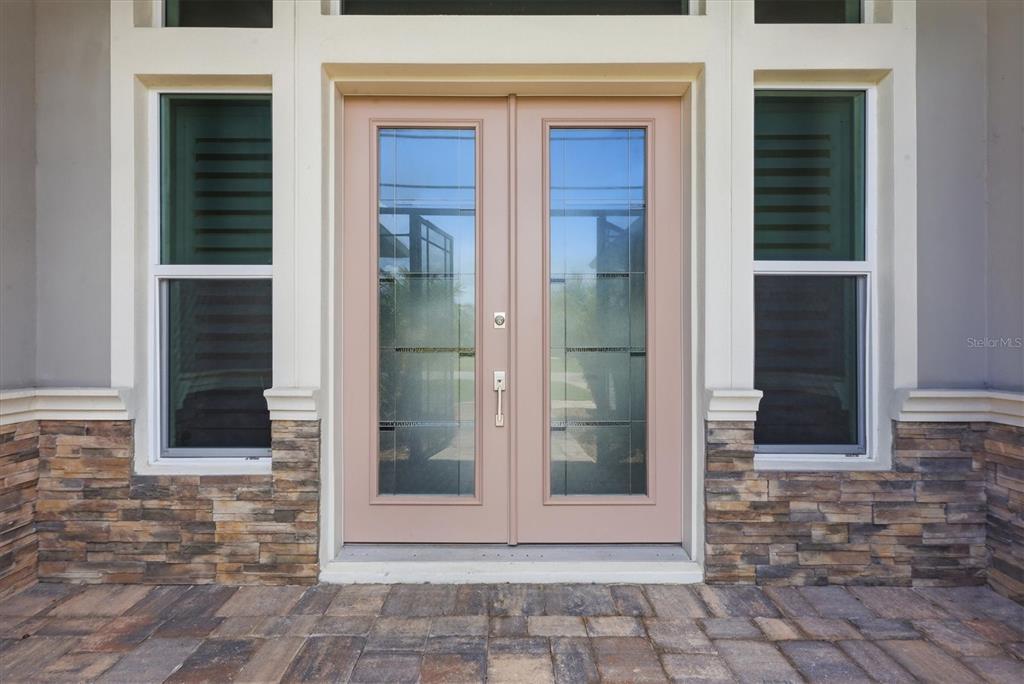 A set of double glass-paneled doors with light pink frames sits between two windows — 15530 STAUNTON CIRCLE, PORT CHARLOTTE, FL