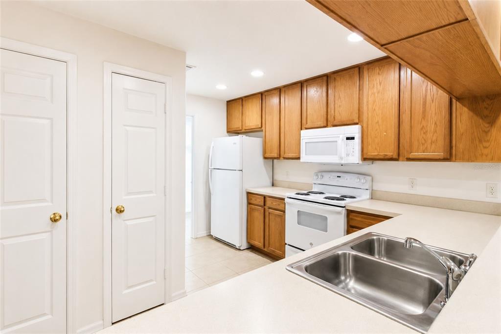 A kitchen with wood cabinets, white appliances, a double sink, and light-colored countertops — 702 E MADISON STREET, PLANT CITY, FL