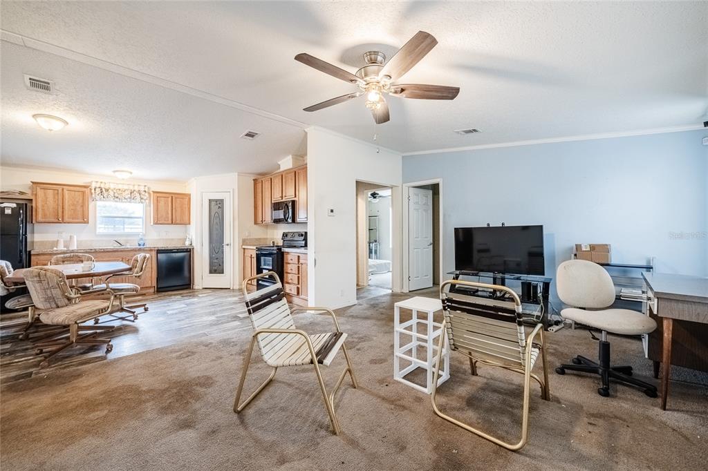 A living room with brown carpet flows into a kitchen with wood cabinets and appliances — 2308 KAY STREET, LAKE ALFRED, FL