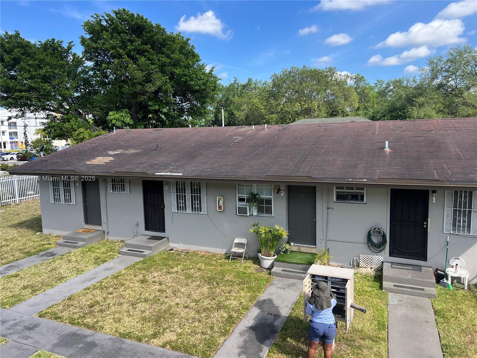 An exterior view of a single-story multi-unit residential building with a grey facade — 5100 NW 23rd Ave # 5, Miami FL 33142, MIAMI, FL