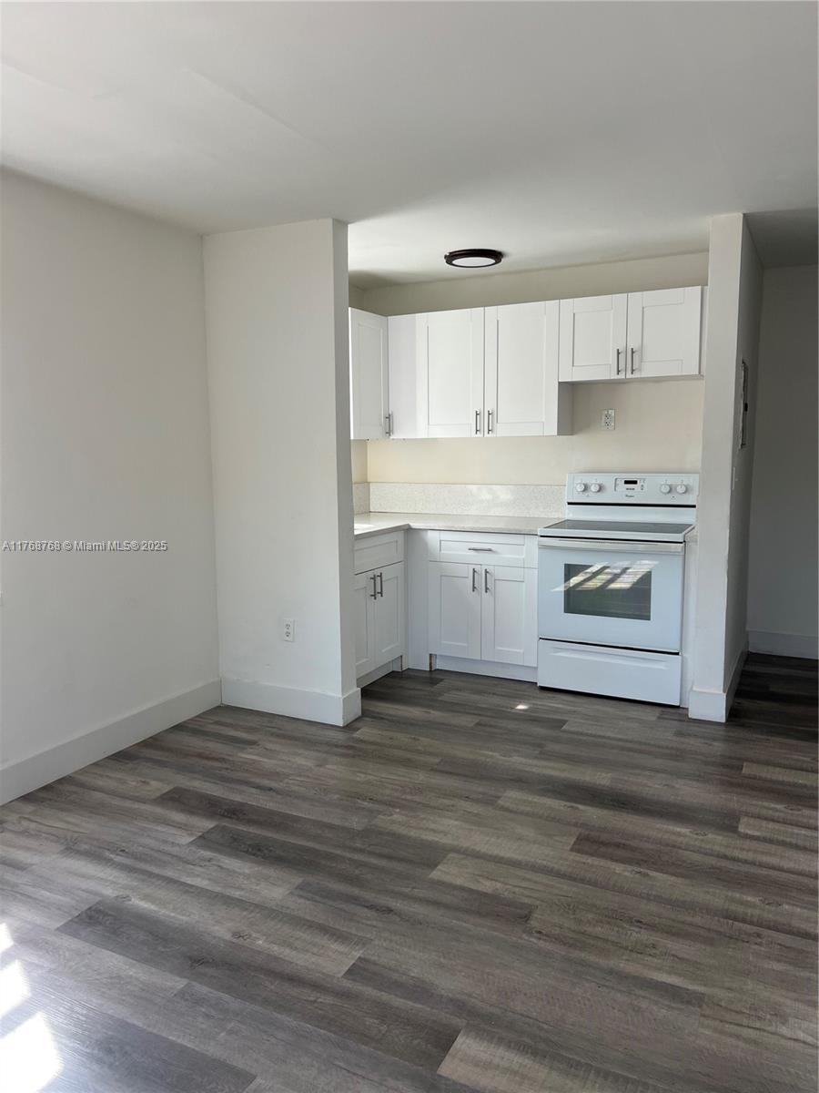A kitchen features white cabinets, a white stove, and gray wood-look flooring — 5100 NW 23rd Ave # 5, Miami FL 33142, MIAMI, FL