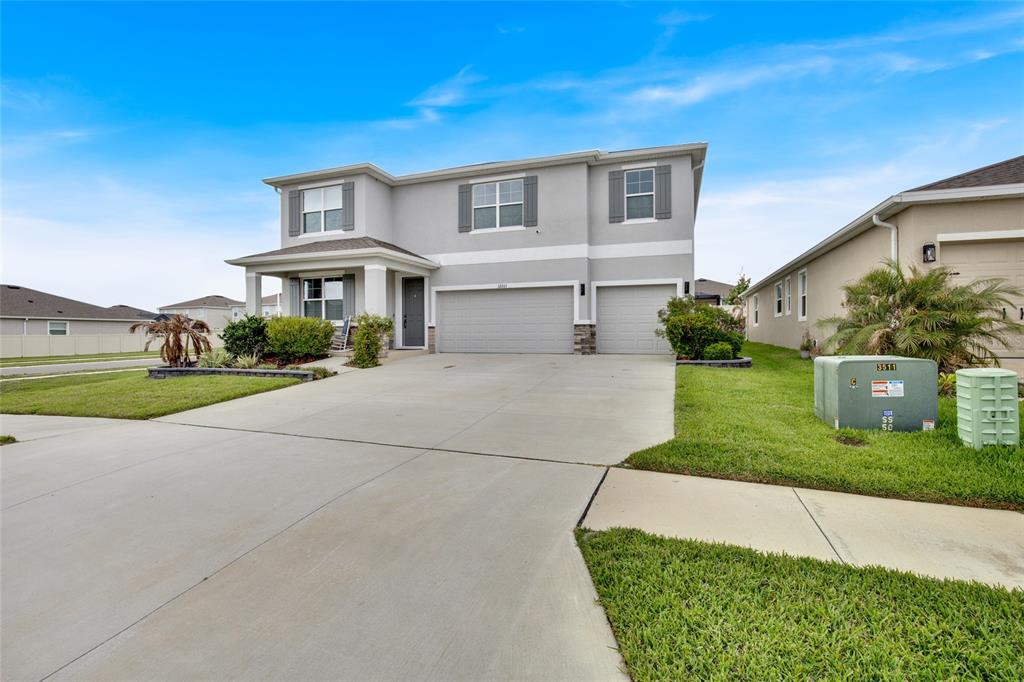 A two-story suburban house with a gray exterior, a three-car garage, and a concrete driveway — 32265 CONCHSHELL SAIL STREET, WESLEY CHAPEL, FL