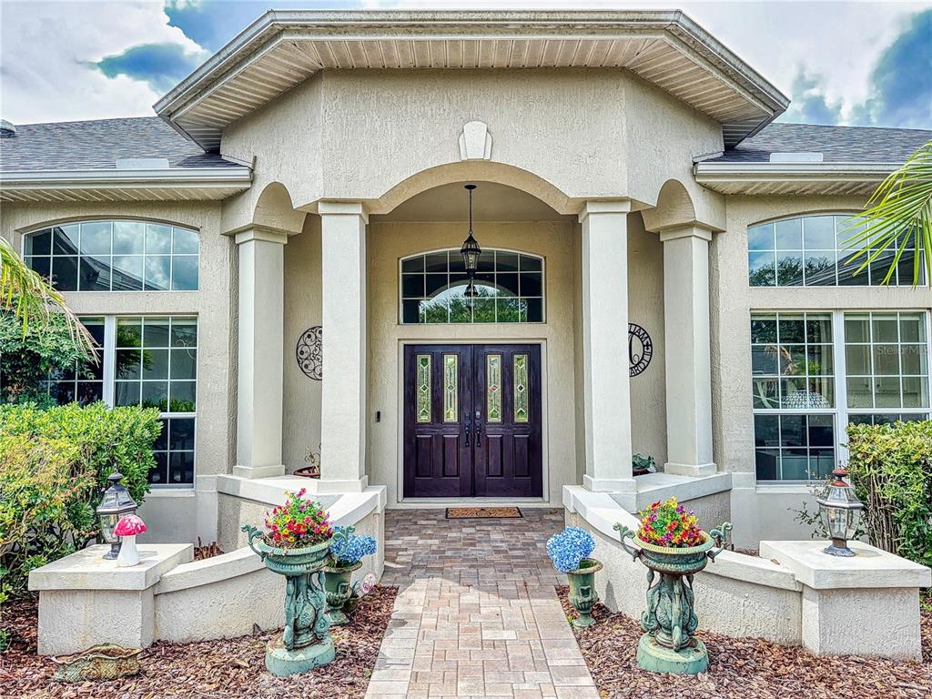 The exterior of a house features a stone walkway leading to double front doors — 649 TERNBERRY FOREST DRIVE, THE VILLAGES, FL