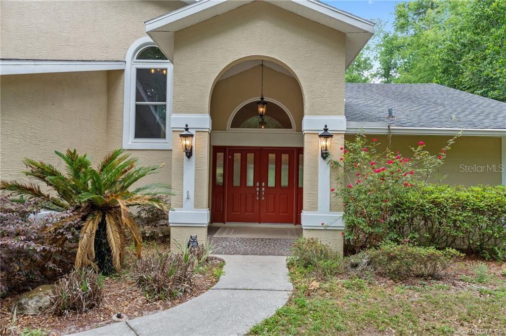 The exterior of a house features a covered entryway with a red double door — 2853 W SUNRISE STREET, LECANTO, FL