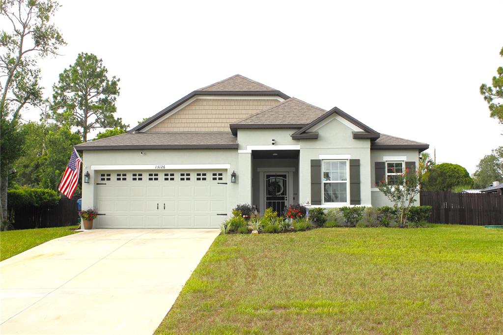 A single-story suburban house with a light green exterior, a two-car garage, and a lawn — 13126 SANTEE STREET, SPRING HILL, FL