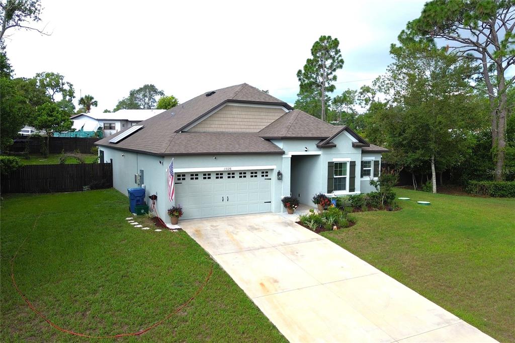 An aerial view of a single-story house with a light blue exterior and a concrete driveway — 13126 SANTEE STREET, SPRING HILL, FL