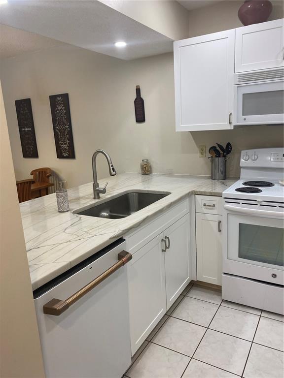 A kitchen features white cabinets, a stainless steel sink, and a white electric range — 622 BIRD BAY DRIVE S UNIT 203, VENICE, FL