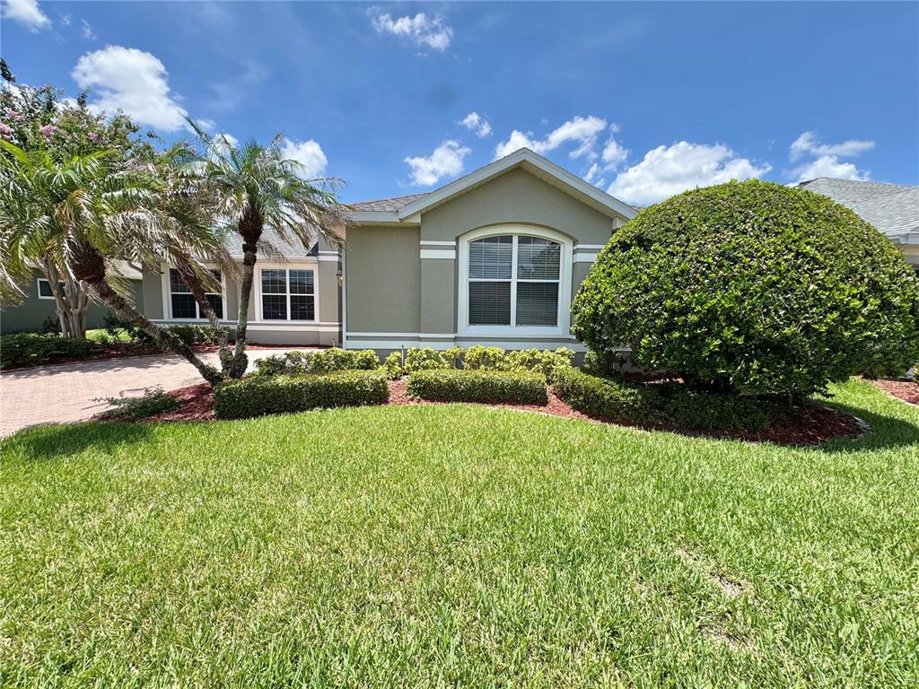 A single-story house with a beige exterior, a large round bush, and a palm tree — 2820 TRADITIONS BOULEVARD S, WINTER HAVEN, FL