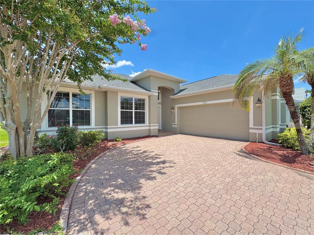 A single-story house with a beige stucco exterior, a paved driveway, and a two-car garage — 2820 TRADITIONS BOULEVARD S, WINTER HAVEN, FL