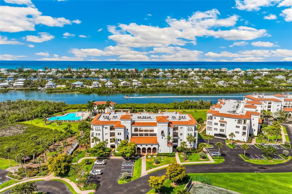 An aerial view shows a multi-story building with a red tile roof near a waterway — 11200 HACIENDA DEL MAR BOULEVARD UNIT 306, PLACIDA, FL
