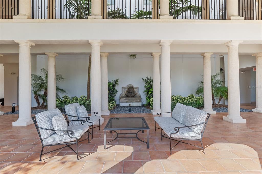 A covered outdoor patio features tiled flooring, seating, and a stone fountain between columns — 11200 HACIENDA DEL MAR BOULEVARD UNIT 306, PLACIDA, FL