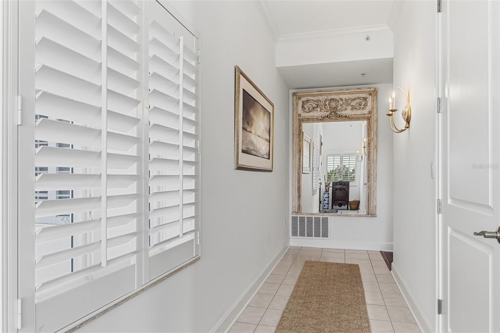 A bright hallway features white walls, tile flooring, a runner rug, and a large ornate mirror — 11200 HACIENDA DEL MAR BOULEVARD UNIT 306, PLACIDA, FL