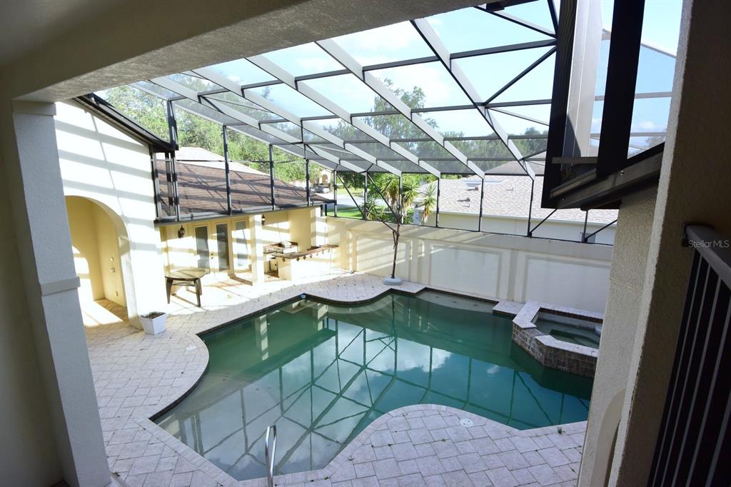 An elevated view of a screened-in swimming pool and patio area with an outdoor kitchen — 285 WOODSTREAM WAY, SPRING HILL, FL