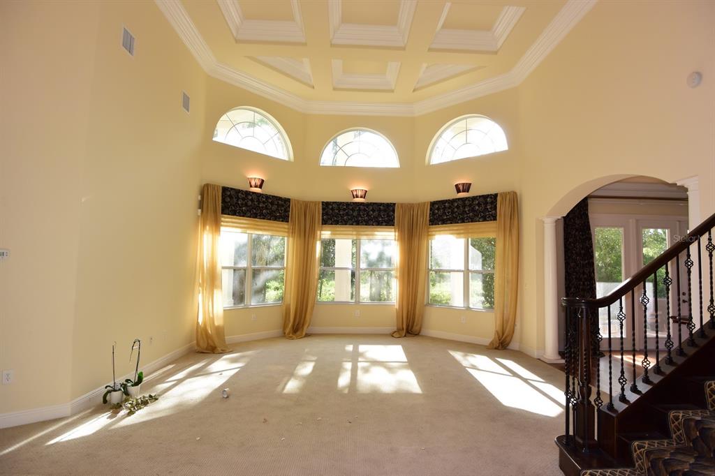A living room with high ceilings, a coffered ceiling, large windows, and a staircase — 285 WOODSTREAM WAY, SPRING HILL, FL