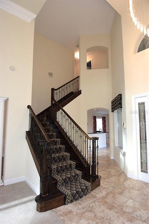 A grand foyer features a carpeted staircase with dark wood railings and tile flooring — 285 WOODSTREAM WAY, SPRING HILL, FL