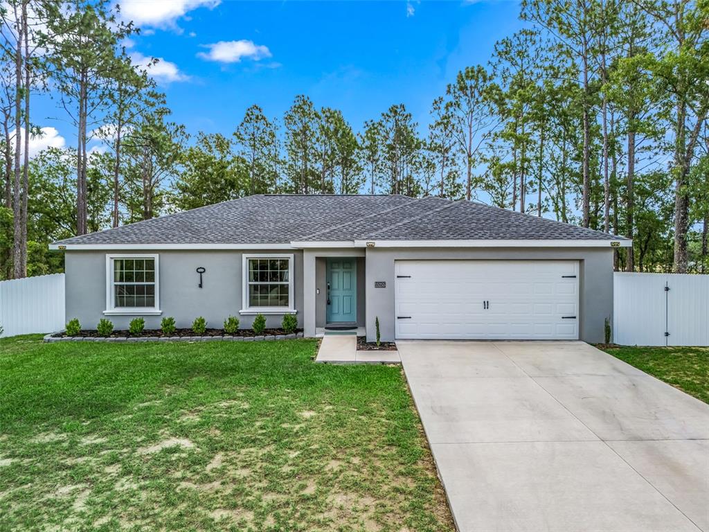 A single-story gray house with a white garage door and a teal front door — 15255 SW 50TH AVENUE ROAD, OCALA, FL