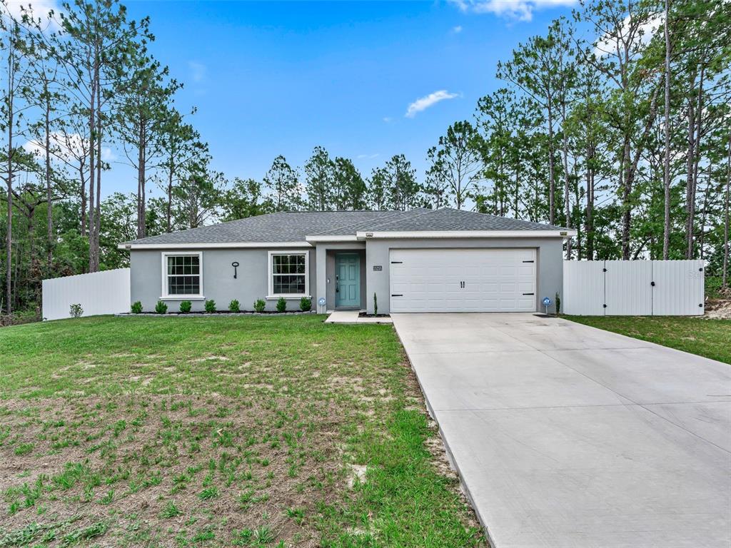 A single-story gray house with a white garage door and a white vinyl fence — 15255 SW 50TH AVENUE ROAD, OCALA, FL