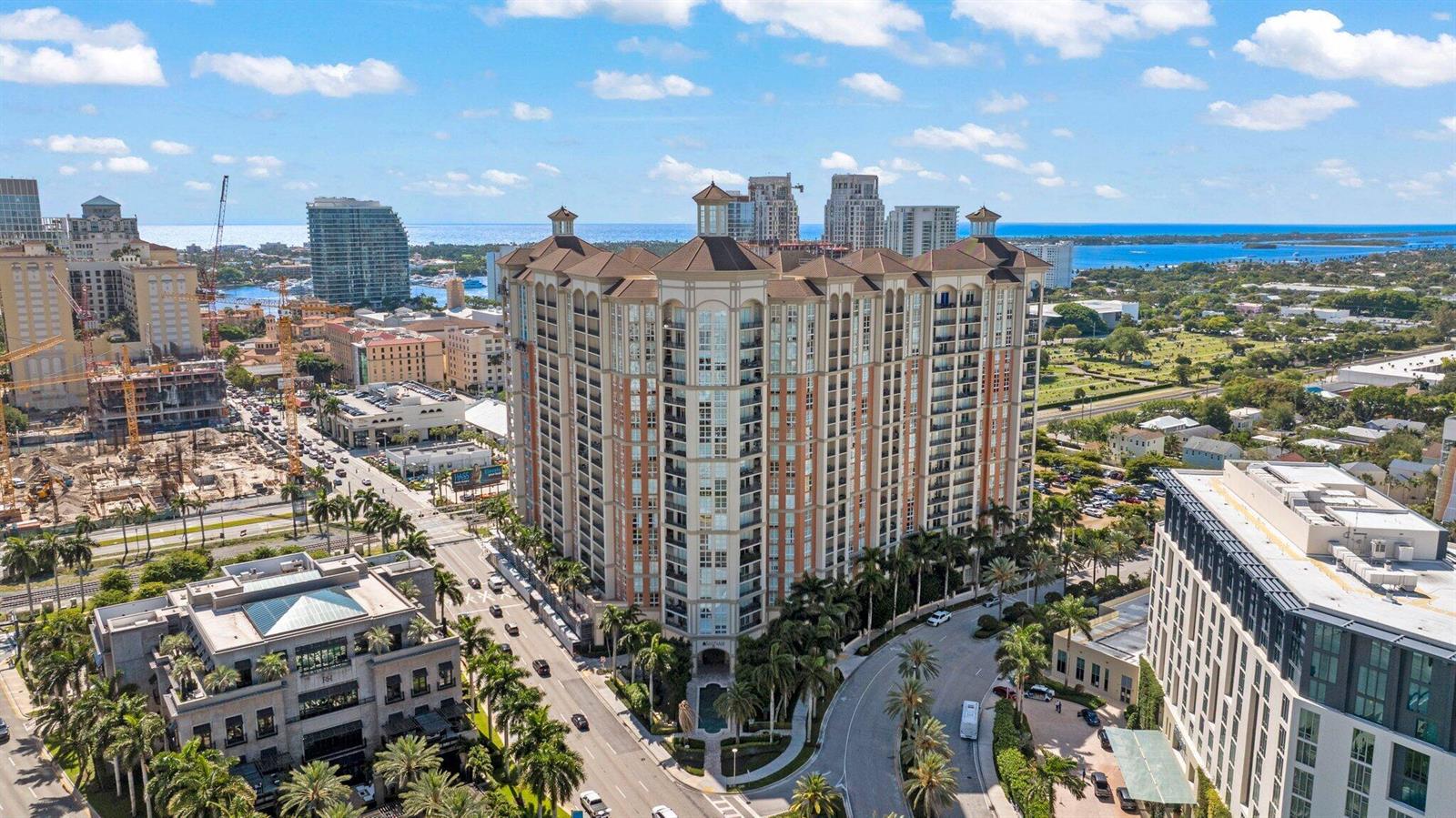An aerial view shows a large, multi-story residential building surrounded by palm trees and streets — 550 Okeechobee Boulevard # 06, West Palm Beach FL 33401, WEST PALM BEACH, FL
