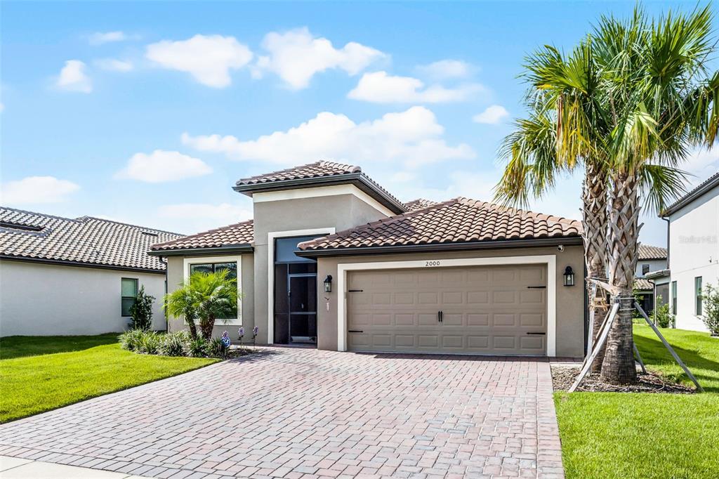 A single-story house with a tan stucco exterior, a tiled roof, and a paved driveway — 2000 GOBLET COVE STREET, KISSIMMEE, FL