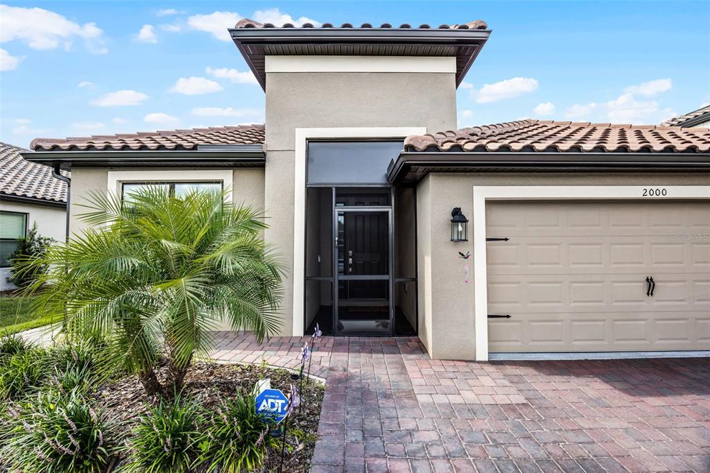 A single-story house exterior features a tan stucco facade, a tiled roof, and a garage — 2000 GOBLET COVE STREET, KISSIMMEE, FL