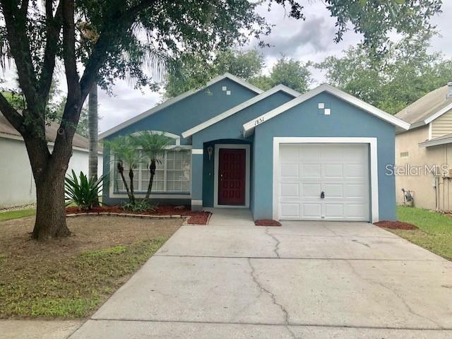 A blue single-story house with a white garage door and a red front door — 1851 FALLING STAR LANE, LUTZ, FL