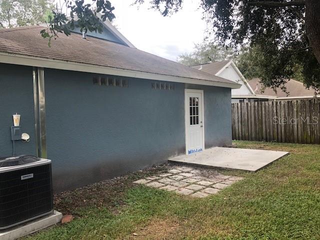 The exterior of a house features a blue wall, a white door, and an air conditioner — 1851 FALLING STAR LANE, LUTZ, FL