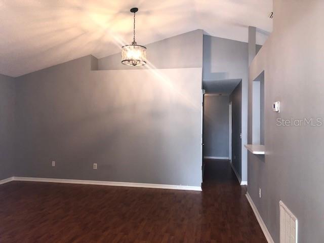 A room with gray walls, dark wood-look flooring, and a hanging pendant light fixture — 1851 FALLING STAR LANE, LUTZ, FL