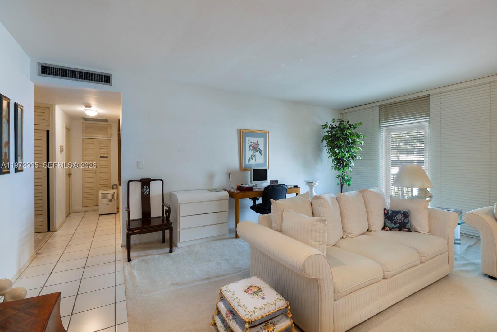 A living room features a white sofa, a desk area, and a tiled entryway — 1408 Brickell Bay Dr # 414, Miami FL 33131, MIAMI, FL