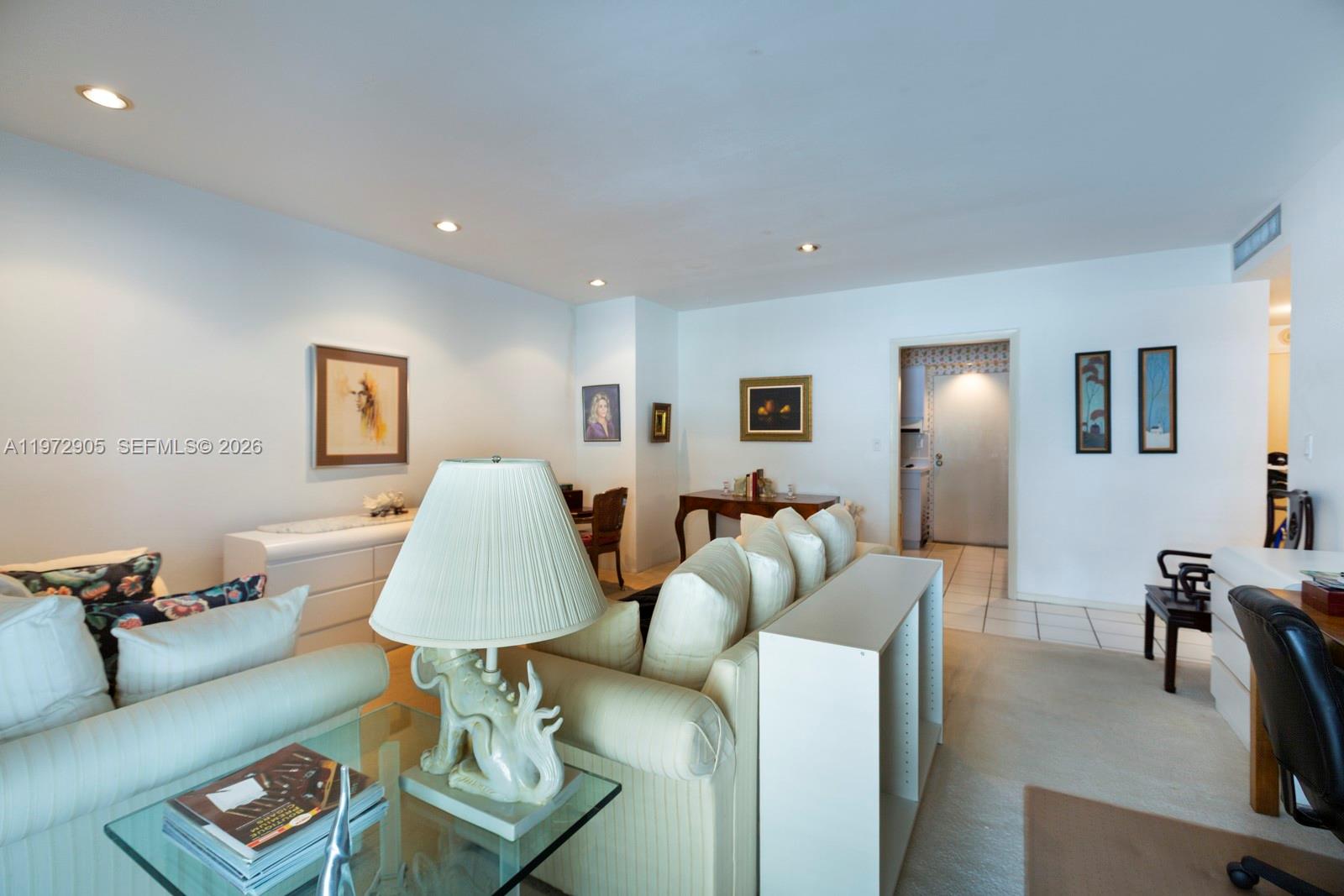 A living room features a white sofa, a glass coffee table, and framed wall art — 1408 Brickell Bay Dr # 414, Miami FL 33131, MIAMI, FL