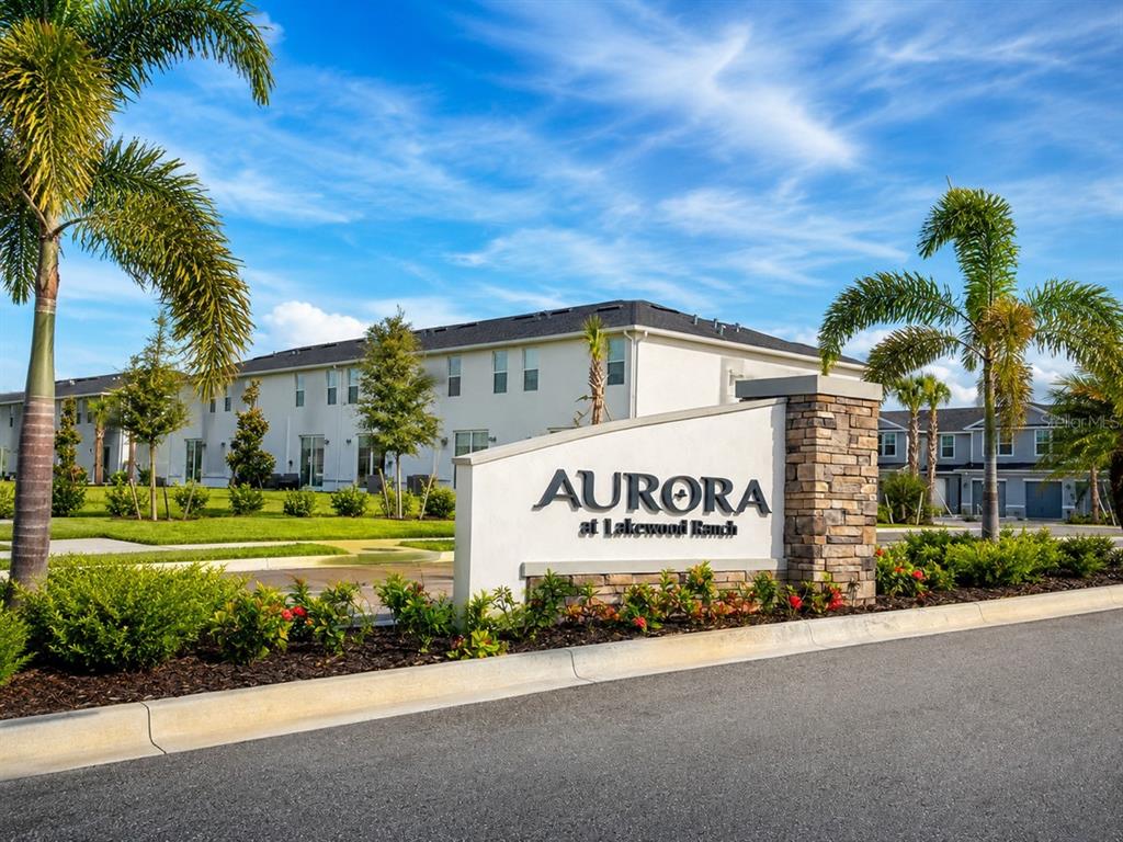 A stone and stucco monument sign for Aurora at Lakewood Ranch stands before apartment buildings — 14322 LILAC SKY TERRACE, BRADENTON, FL