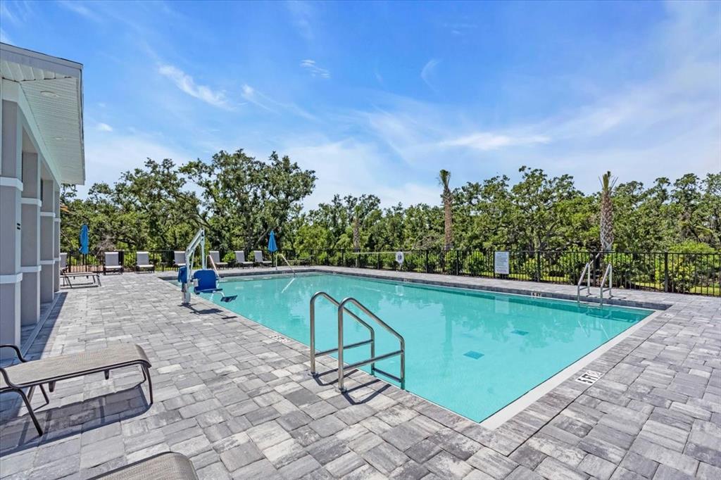 A rectangular outdoor swimming pool features a paved deck, lounge chairs, and a lift chair — 14322 LILAC SKY TERRACE, BRADENTON, FL