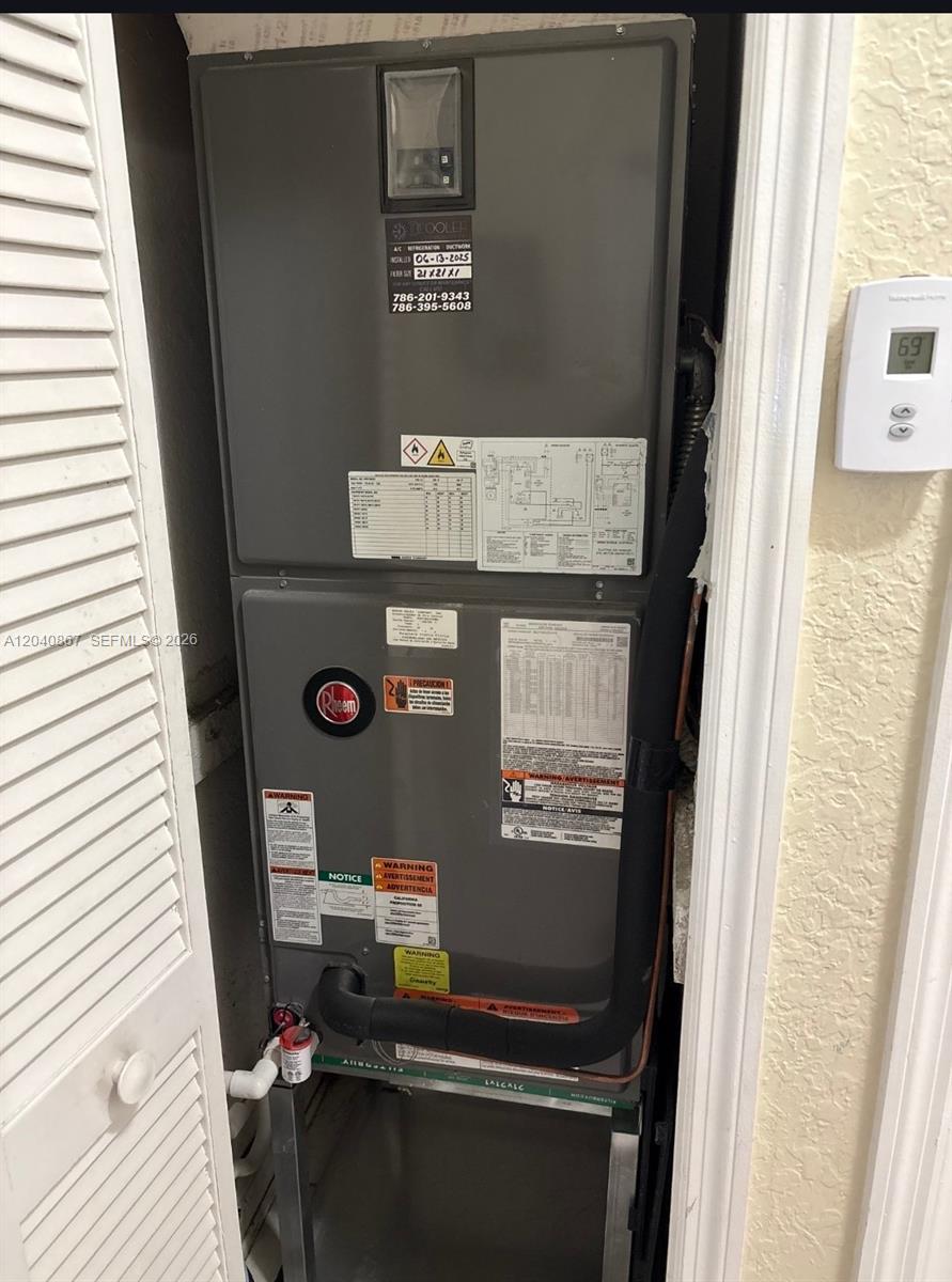 A Rheem air handler unit is installed in a utility closet next to a thermostat — 8741 NW 141st Ter, Miami Lakes FL 33018, MIAMI LAKES, FL