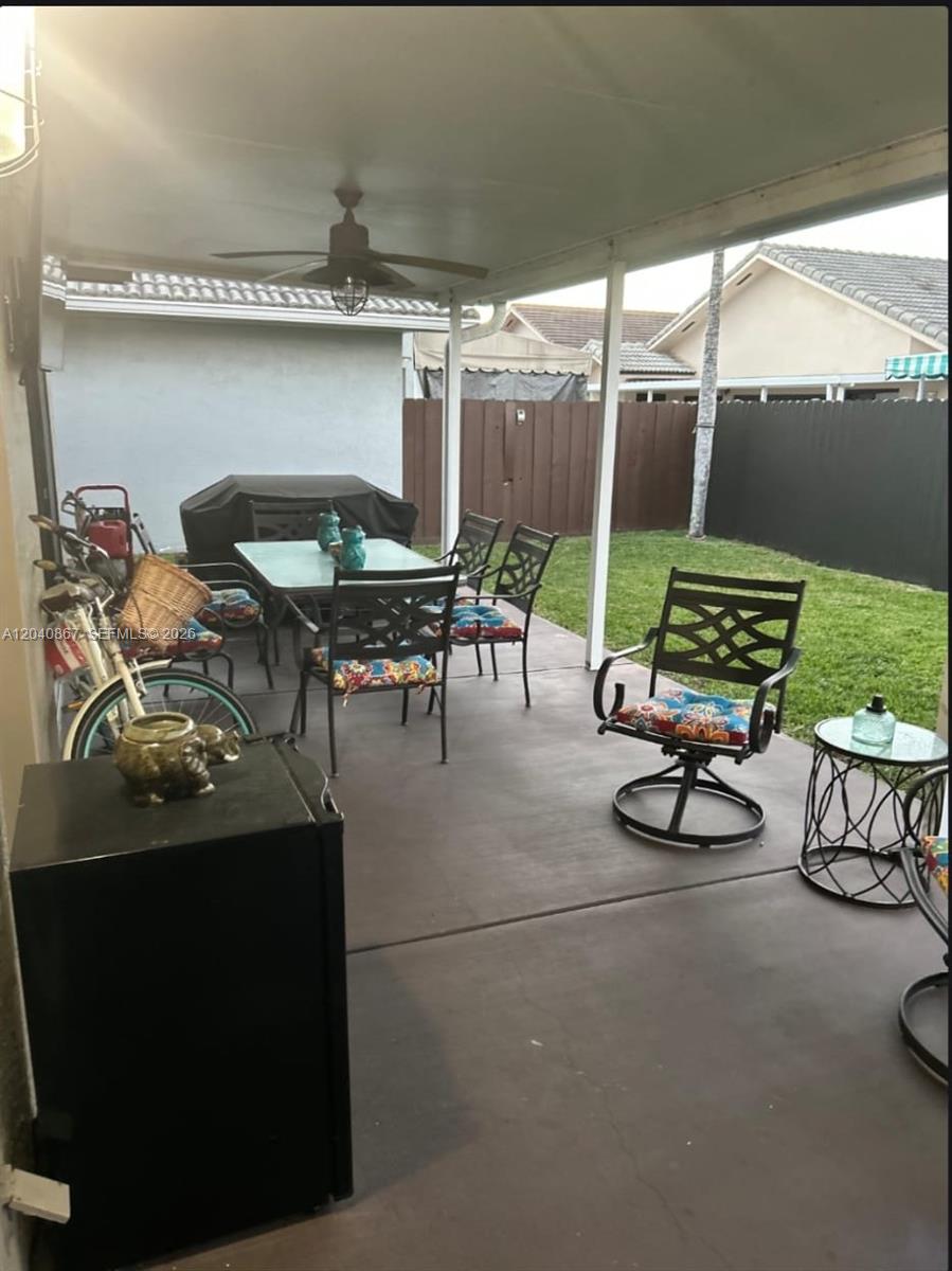 A covered concrete patio features outdoor dining furniture, a grill, and a grassy backyard — 8741 NW 141st Ter, Miami Lakes FL 33018, MIAMI LAKES, FL