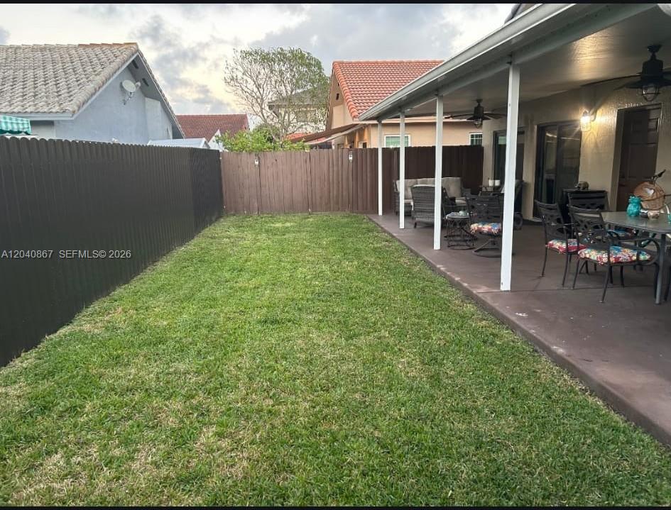 A backyard features a grassy lawn, a covered patio with furniture, and a privacy fence — 8741 NW 141st Ter, Miami Lakes FL 33018, MIAMI LAKES, FL
