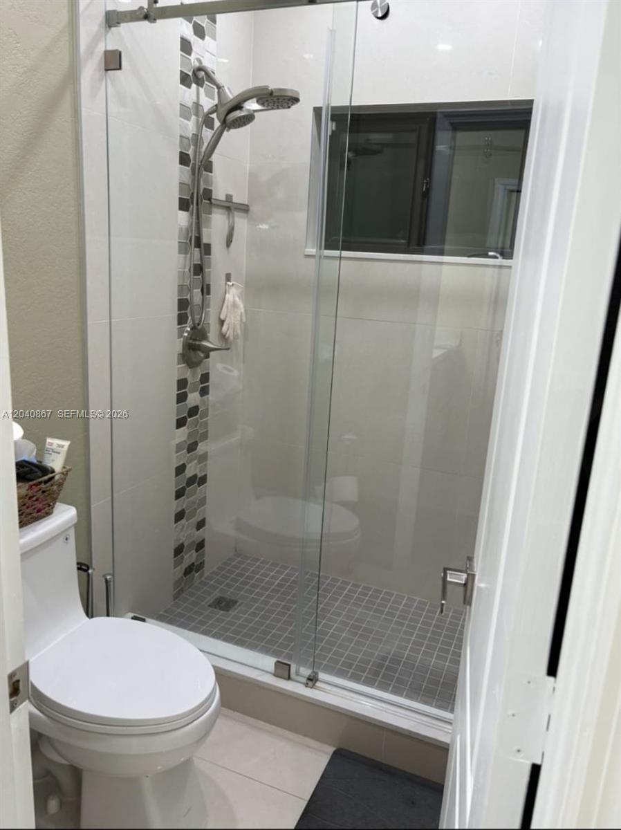 A bathroom features a glass-enclosed shower with mosaic tile accents and a white toilet — 8741 NW 141st Ter, Miami Lakes FL 33018, MIAMI LAKES, FL