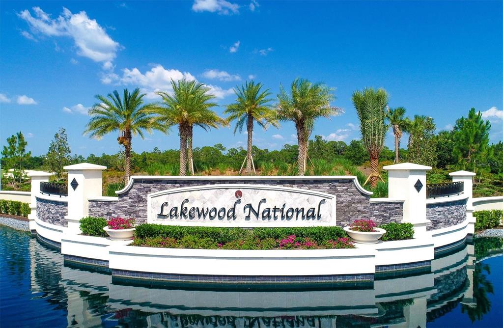 The entrance sign for Lakewood National stands in front of a pond with palm trees — 17810 GAWTHROP DRIVE UNIT 203, LAKEWOOD RANCH, FL