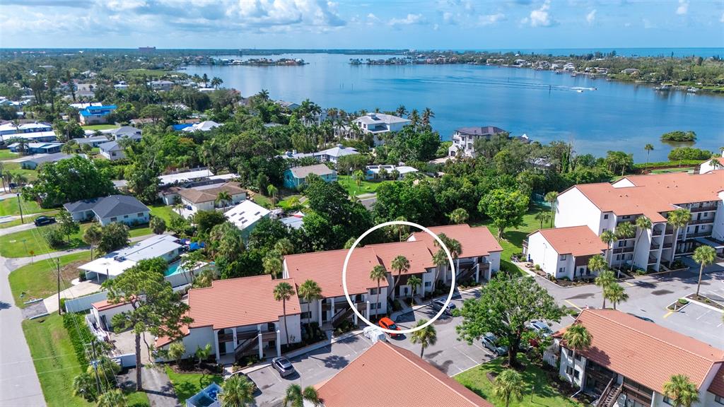 An aerial view shows a multi-story apartment complex with red tile roofs near water — 1646 STICKNEY POINT ROAD UNIT 101, SARASOTA, FL