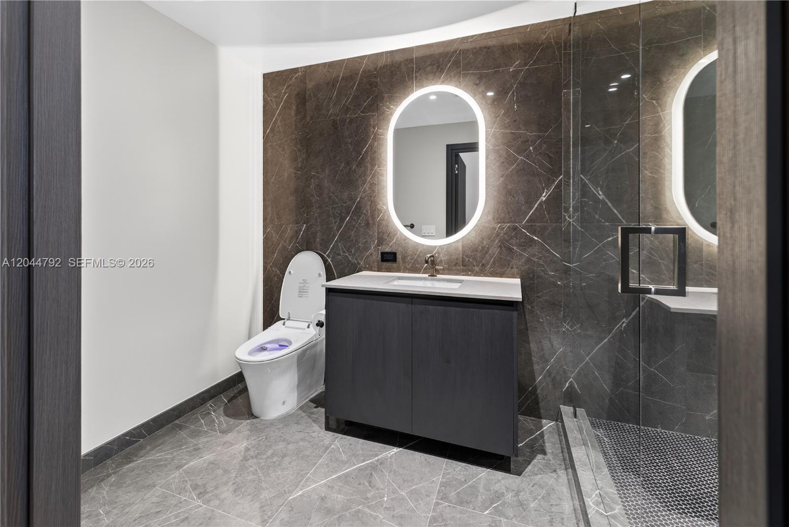 A modern bathroom features a dark marble accent wall, a floating vanity, and a glass shower — 20 NE 11th # 4703, Miami FL 33132, MIAMI, FL