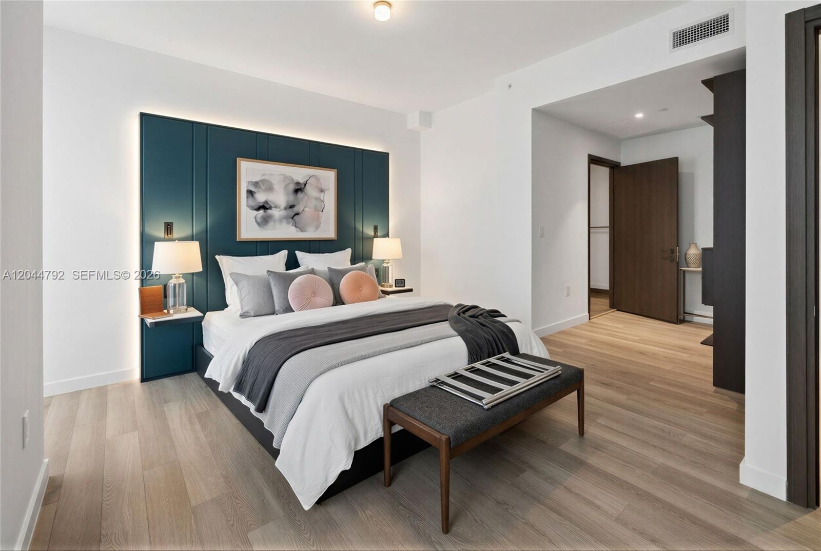 A modern bedroom features a teal paneled accent wall, a platform bed, and wood flooring — 20 NE 11th # 4703, Miami FL 33132, MIAMI, FL