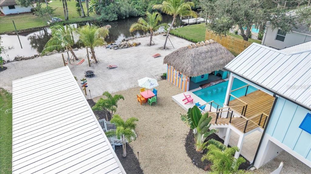 An aerial view shows a house with a pool, tiki bar, and sandy backyard area — 9470 COLONY DRIVE, NORTH FORT MYERS, FL