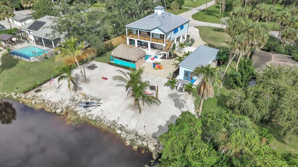 An aerial view of a waterfront property featuring a two-story house, tiki hut, and beach — 9470 COLONY DRIVE, NORTH FORT MYERS, FL