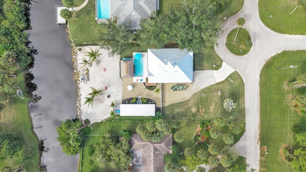 An aerial view shows a house with a pool, a canal, and a detached garage — 9470 COLONY DRIVE, NORTH FORT MYERS, FL